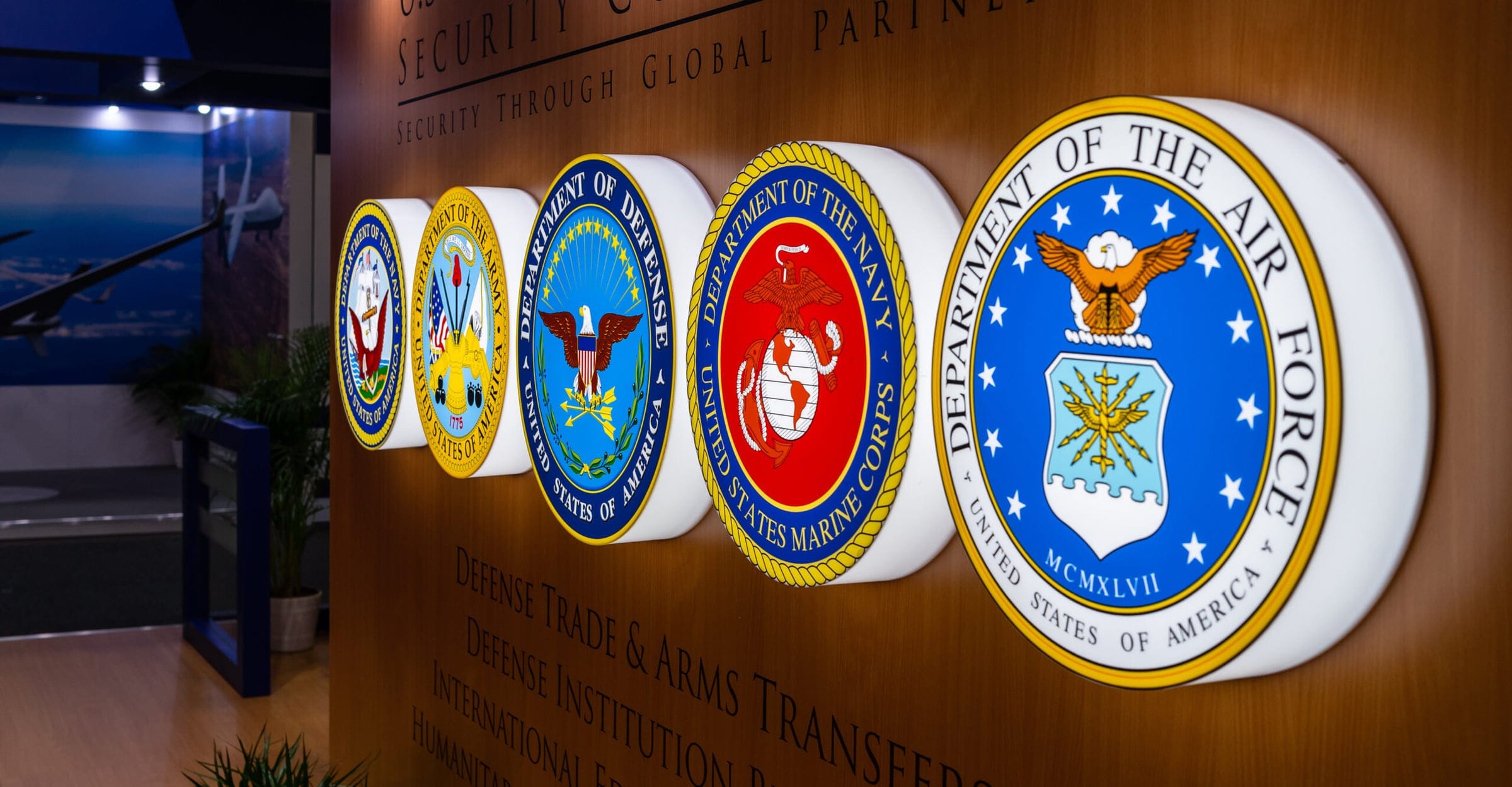 Illuminated seals of U.S. military departments mounted on a wood-panelled wall