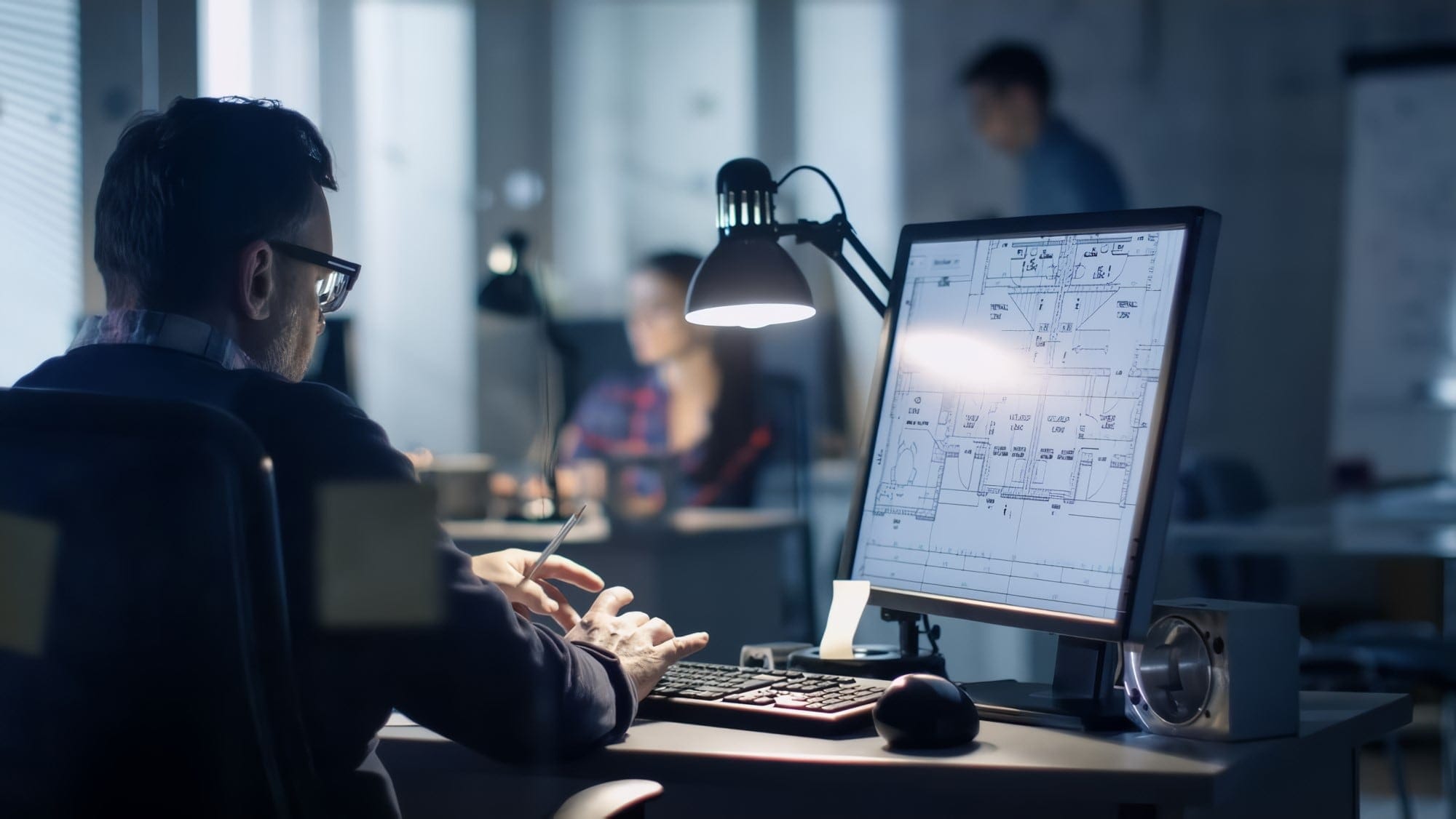 Estimator working at a desk with drawings displayed on a computer monitor