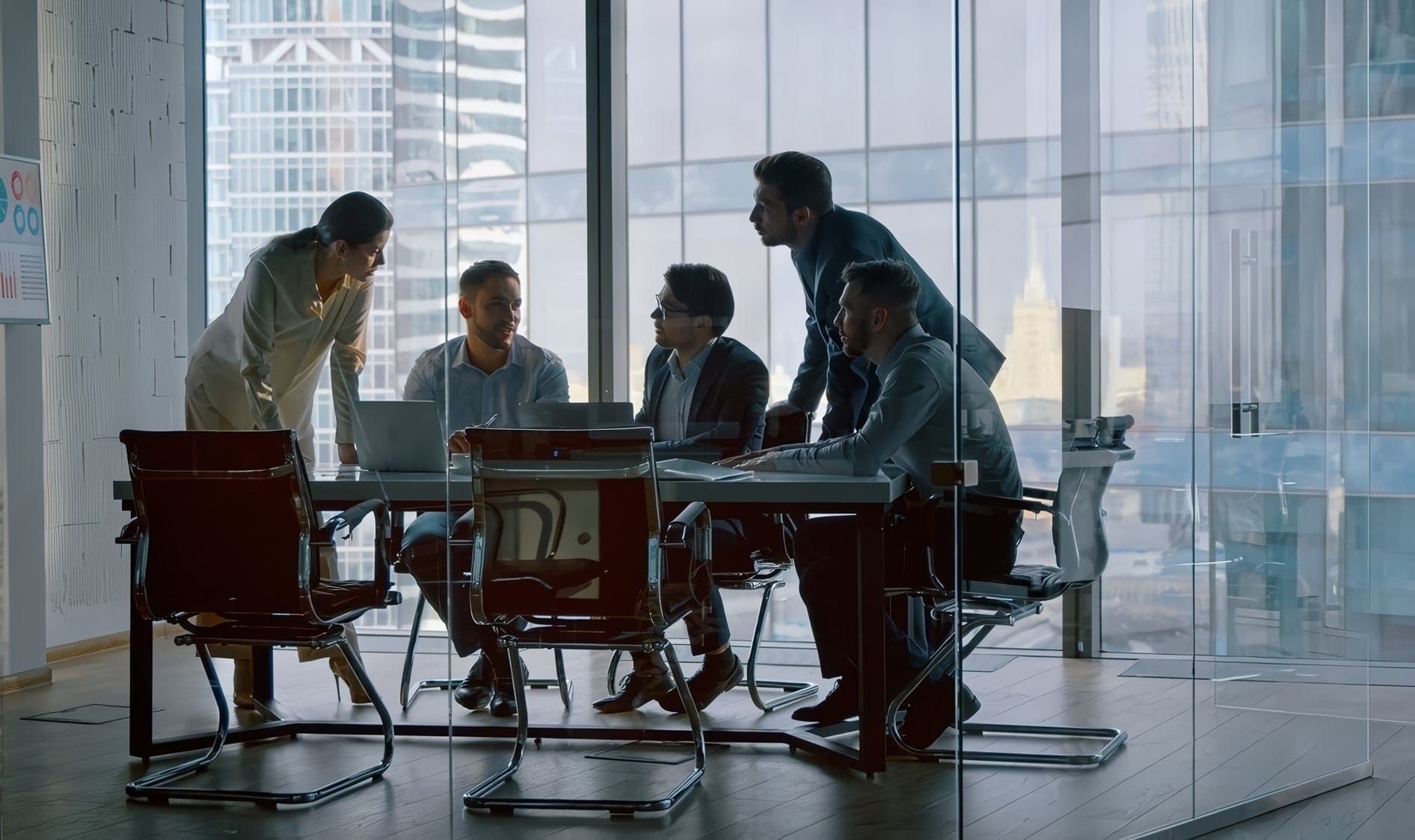 Project team meeting around a conference table in a glass-walled office
