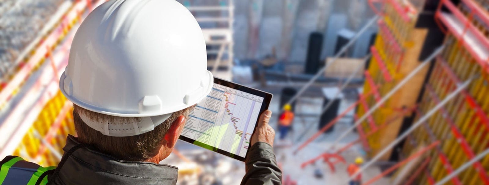 Construction professional in a hard hat reviewing a schedule on a tablet